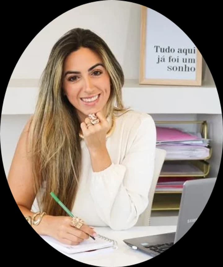 Retrato da psicóloga Karol Mello sorrindo à mesa de trabalho